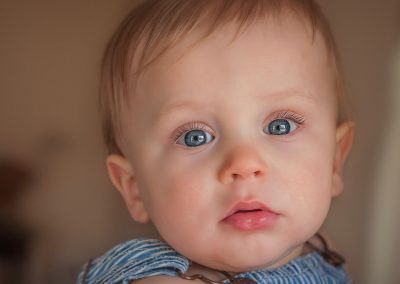 First and Forever Photography, Iveta Dietz, photography by Iveta Dietz, blue eyes, baby, baby boy, brown background, best newborn photographer, best baby photographer, best St. Charles photographer, St. Louis photographer, posed baby, baby's first year, safe posing, safety first, comfortable posing, cute baby, happy baby, cute look, big eyes, blue overalls